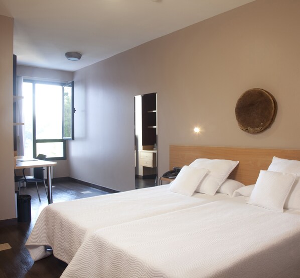 Ein Hotelzimmer mit zwei Betten, einem Schreibtisch und einem Sessel.