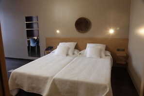 Ein Doppelbett mit Holzüberbau, zwei Kissen, ein Nachttisch und ein an der Wand befestigtes Regal.
