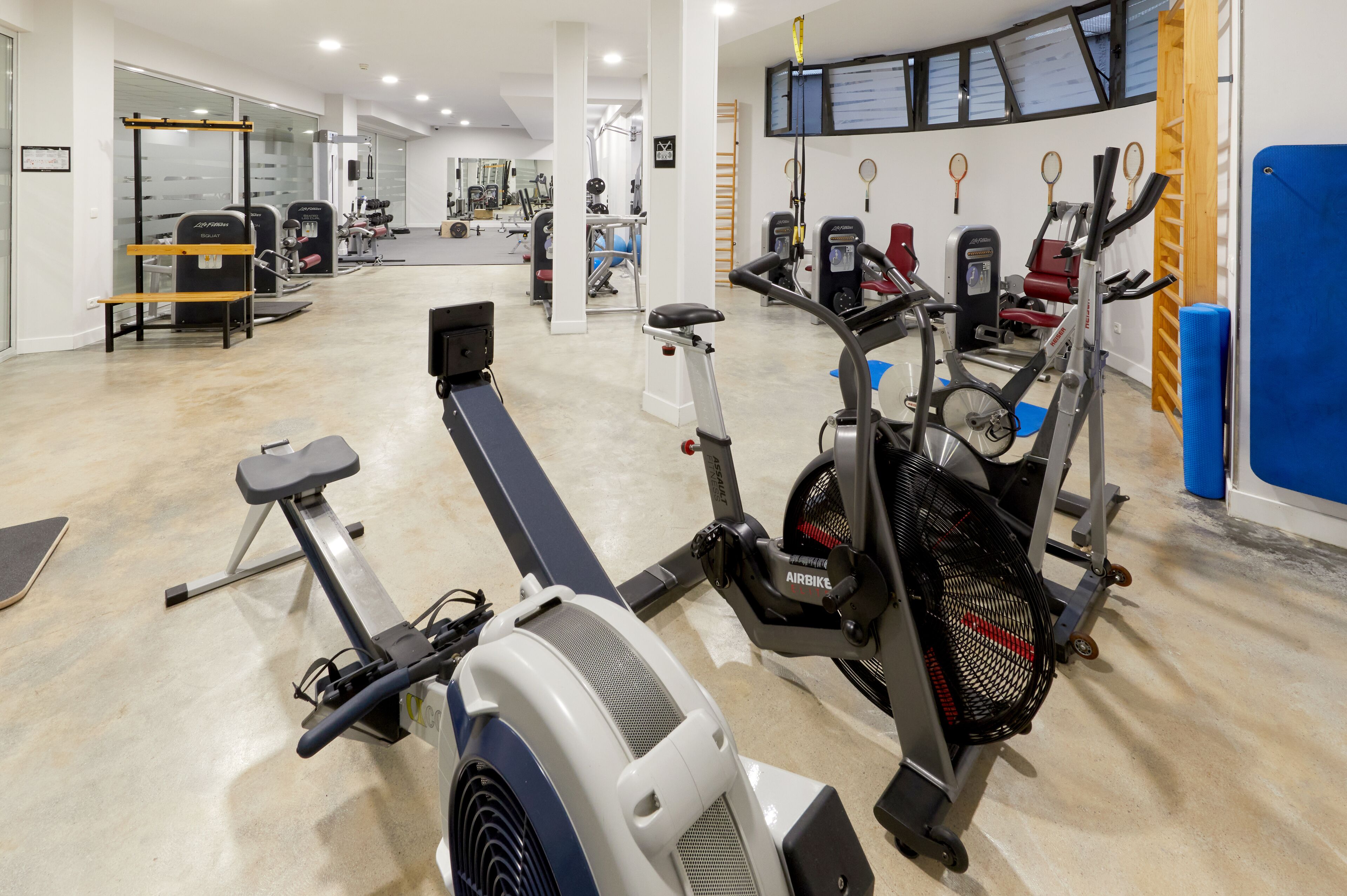 A gym with cardio machines, weight machines, and a mirrored wall.