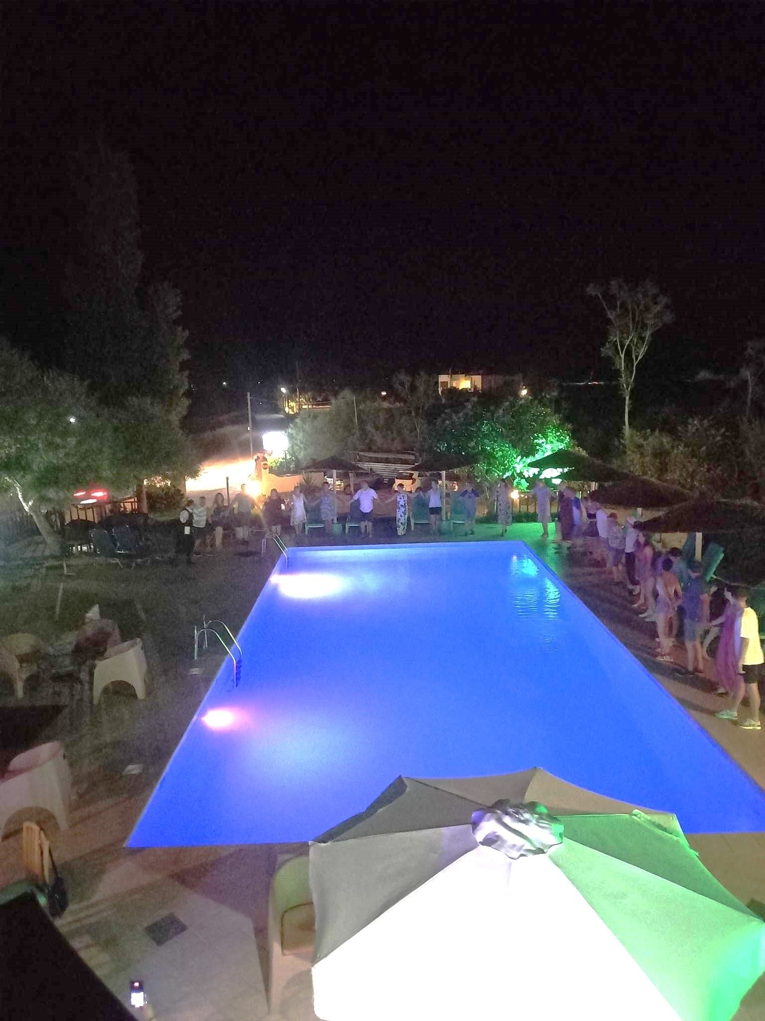 An outdoor swimming pool at night with people around it.