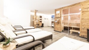 A spa room with three massage beds, wooden cabinets, and a sauna area. - Appartements Auszeit (Lend)