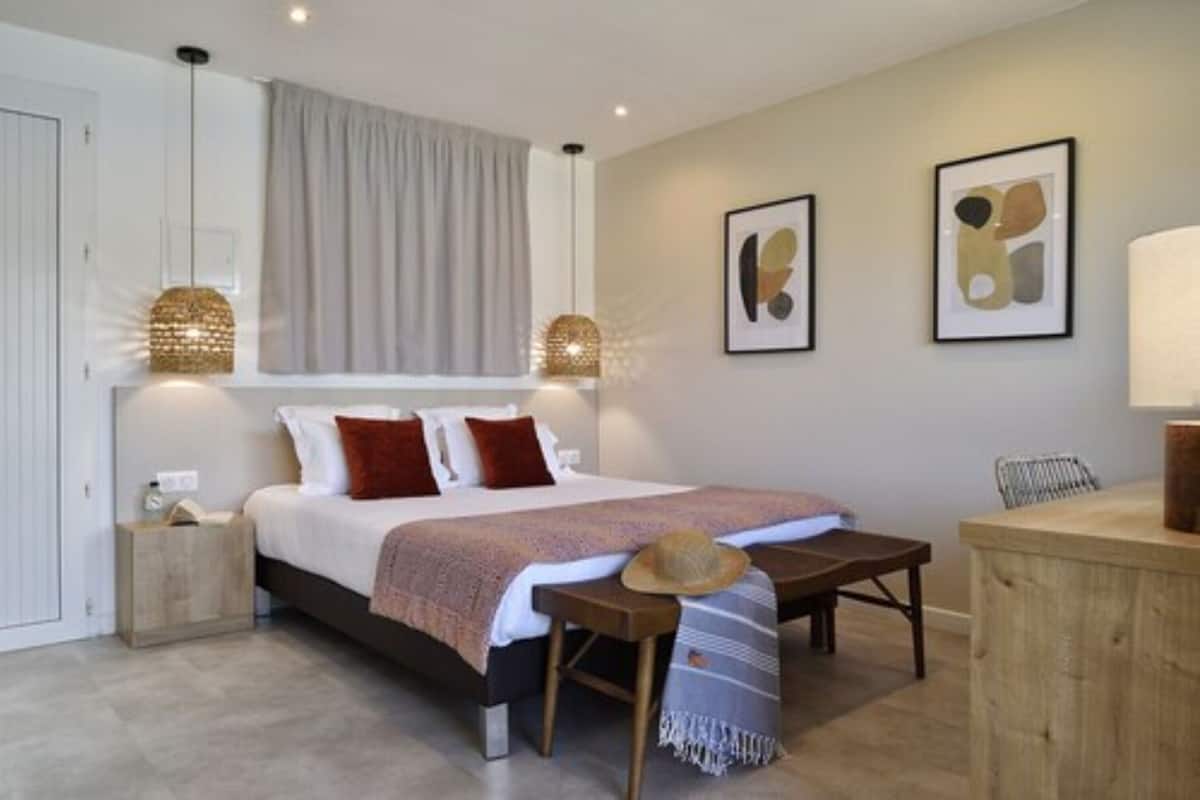 Quarto com cama, mesas de cabeceira, escrivaninha e uma cadeira.