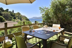 An outdoor dining area with a table and chairs, overlooking a scenic view of the sea and hills. - Hotel Sampiero Corso (Propriano)