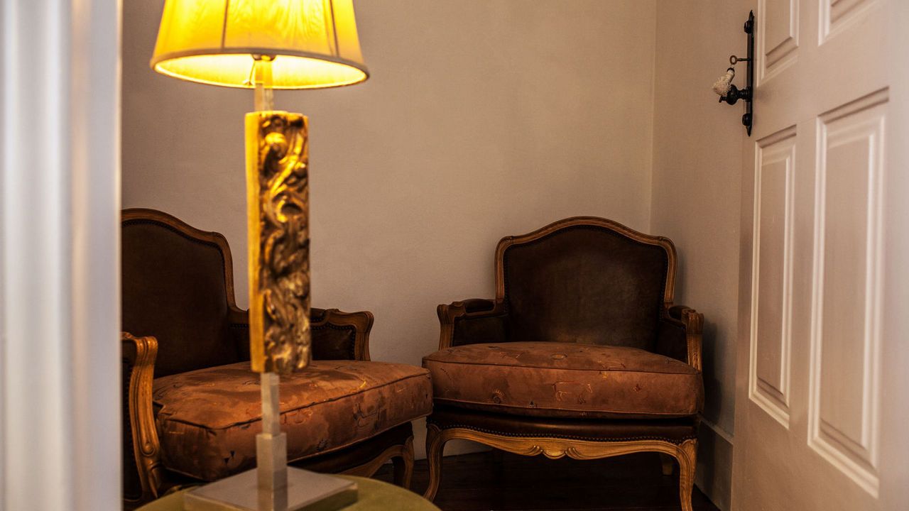A room with two upholstered chairs, a floor lamp, and a white door.