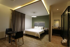 Une chambre d’hôtel comprenant un lit, un bureau, une chaise, une table de chevet et un miroir.