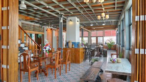 A spacious interior with a high ceiling, exposed beams, and a mix of wooden and tiled flooring.