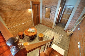 A spacious room with a wooden staircase, a round wooden table with chairs, and a patterned rug on the floor. - Saengpanya Home Boutique Hotel - SHA Plus  (Chiang Mai)