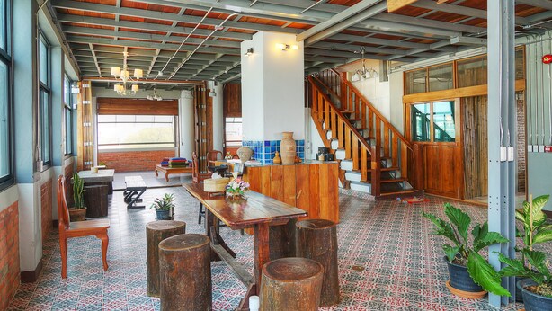 A spacious kitchen with a wooden table, stools, and potted plants.