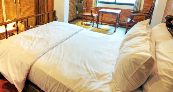 A double bed with white linens in a room with brick walls and wooden furniture. - Saengpanya Home Boutique Hotel - SHA Plus  (Chiang Mai)