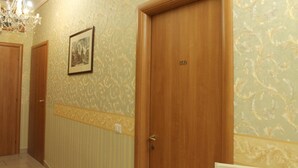 Un couloir avec un papier peint à motifs, un lustre et une porte portant l’inscription « 500 ».