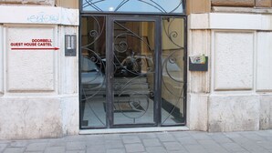 L’entrée d’un hôtel, avec un interphone et une enseigne représentant un château, une porte en métal et une boîte aux lettres.