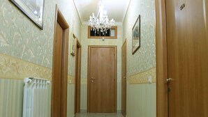 Un couloir avec des portes en bois, un radiateur et un lustre.