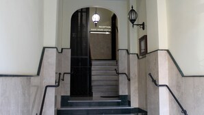 Un escalier menant à un espace d’accueil où un panneau indique : « RÉCEPTION, MAISON D’HÔTES, CHÂTEAU ».