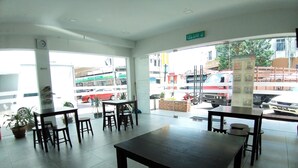 A spacious indoor area with multiple tables and chairs, a clock on the wall, and a view of the street outside. - Hotel Jelai Mentakab (Mentakab)