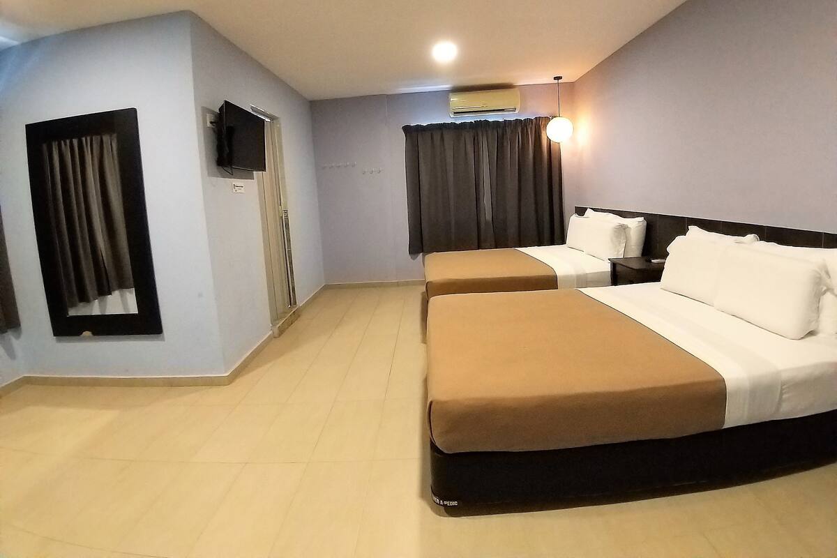 Ein Hotelzimmer mit zwei Betten, einem Flachbildfernseher, einer Klimaanlage und einer Deckenleuchte.