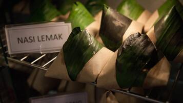 Een presentatie van etenswaren verpakt in bladeren, met de labels 'Nasi Lemak' en 'Mee Goreng'.