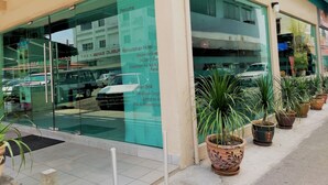 A hotel with a large glass facade, outdoor potted plants, and a sign listing amenities. - Hotel Jelai Mentakab (Mentakab)