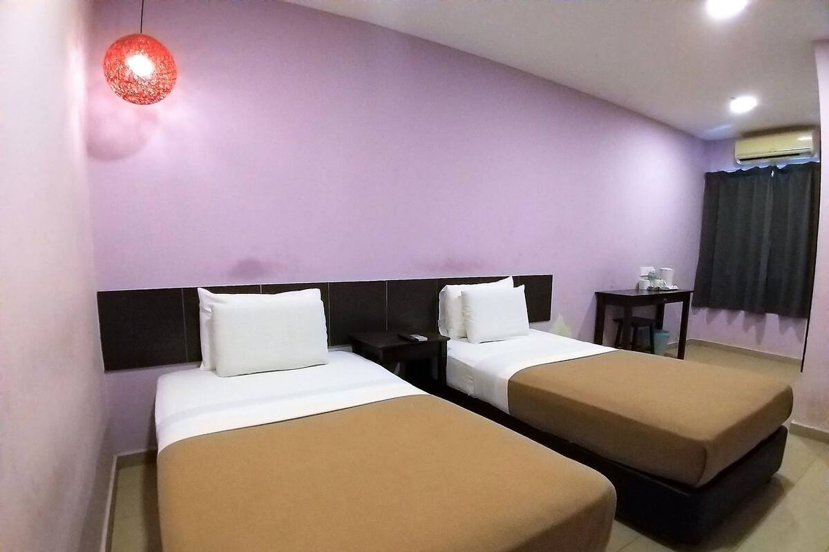 Ein Hotelzimmer mit zwei Betten, einem kleinen Tisch, einem Stuhl und einer Pendelleuchte.