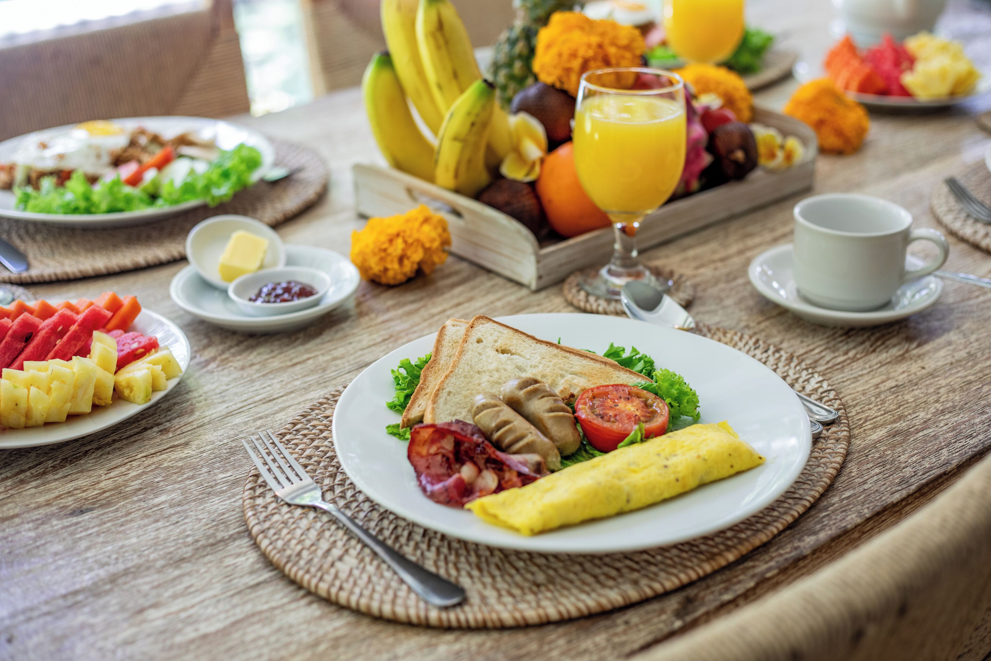 A breakfast setting with various dishes including toast, eggs, tomatoes, and a fruit bowl.
