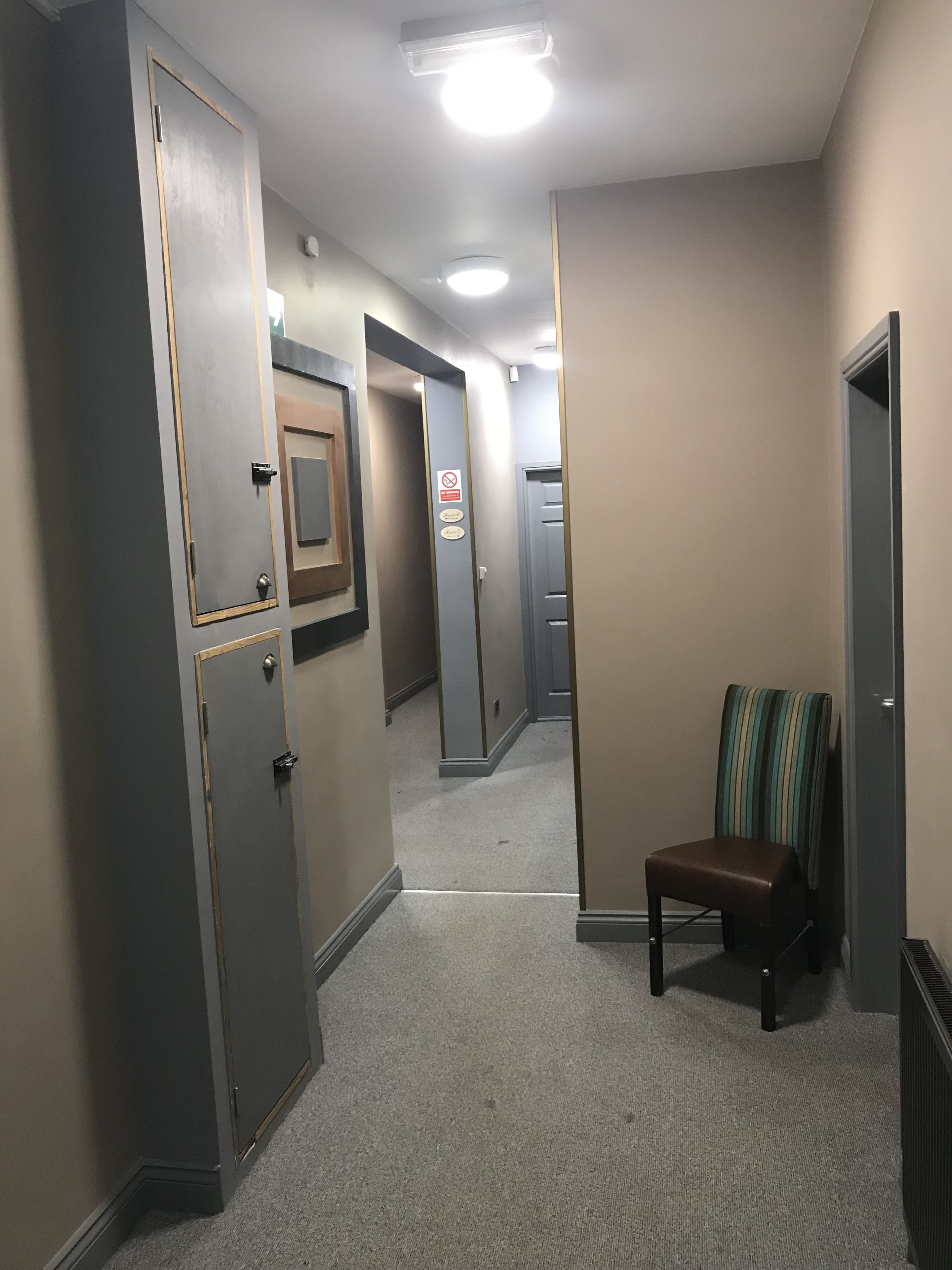 A hallway with a chair, doors, and a sign indicating no smoking.