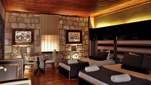 A room with a stone wall, wooden ceiling, two beds with towels, a desk, and a chair. - Kosa Butik Otel (Antalya)