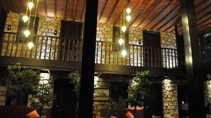 A lobby with stone walls, wooden beams, and hanging light fixtures. - Kosa Butik Otel (Antalya)