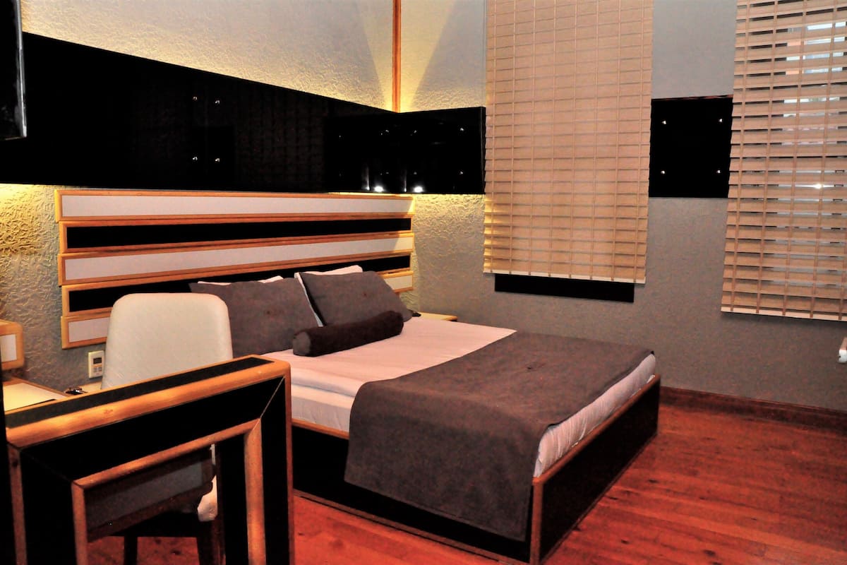 A bedroom with a bed, bedside table, and a desk with a chair.