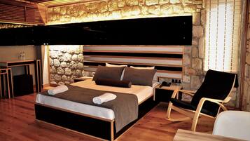 Un dormitorio moderno con pared de piedra, una cama con cabecero de madera, una mesita de noche, una silla y un televisor de pantalla plana montado en la pared.
