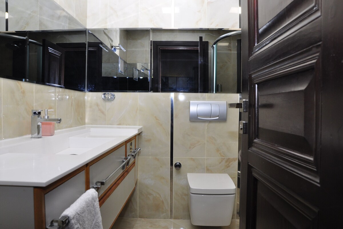 A modern bathroom with a dual sink vanity, a toilet, and a mirror above the sink.