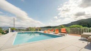 Ein rechteckiger Pool mit weißem Zaun und orangefarbenen Liegestühlen.