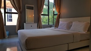 A bedroom with a bed, a dresser, a mirror, and a window with curtains. - Tulip Hotel (Ipoh)
