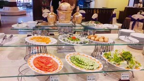 Un bufé con varios platos, incluyendo una ensalada, pepinos en rodajas y un plato etiquetado 'CA CHUA'.