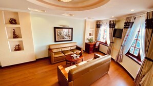 Una sala de estar con sofá, mesa de centro, televisor y ventana con cortinas.