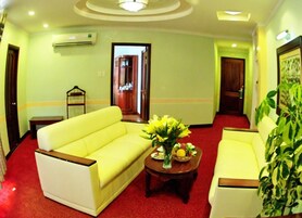 Un vestíbulo de hotel con un sofá amarillo, una mesita con flores y una planta en maceta.
