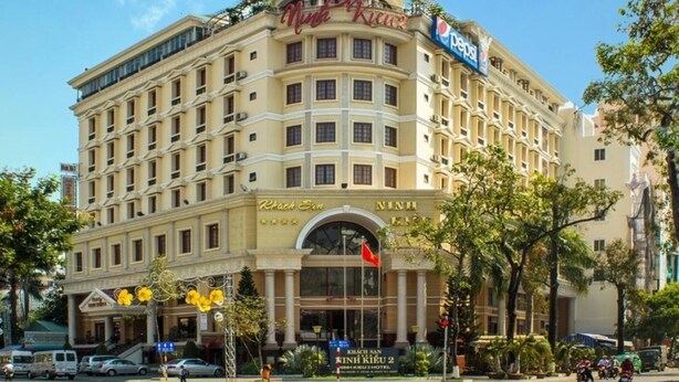 Un hotel con un letrero llamativo que dice "Hotel Nhung Kieu 2" y el logotipo de Pepsi.