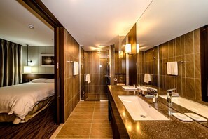 A hotel bathroom with a large mirror, a shower, and a vanity with a sink and towel rack. - Jeju Central City Hotel (Jeju-si,)