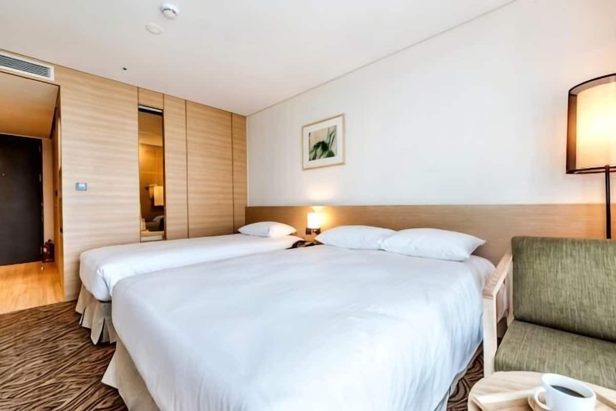 Une chambre d’hôtel avec un grand lit, une chaise, une table de chevet et une lampe.