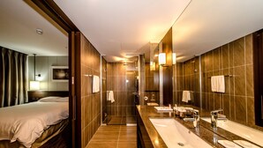 Une salle de bain d’hôtel moderne, dotée d’un long meuble-lavabo, de plusieurs vasques et d’un espace douche.