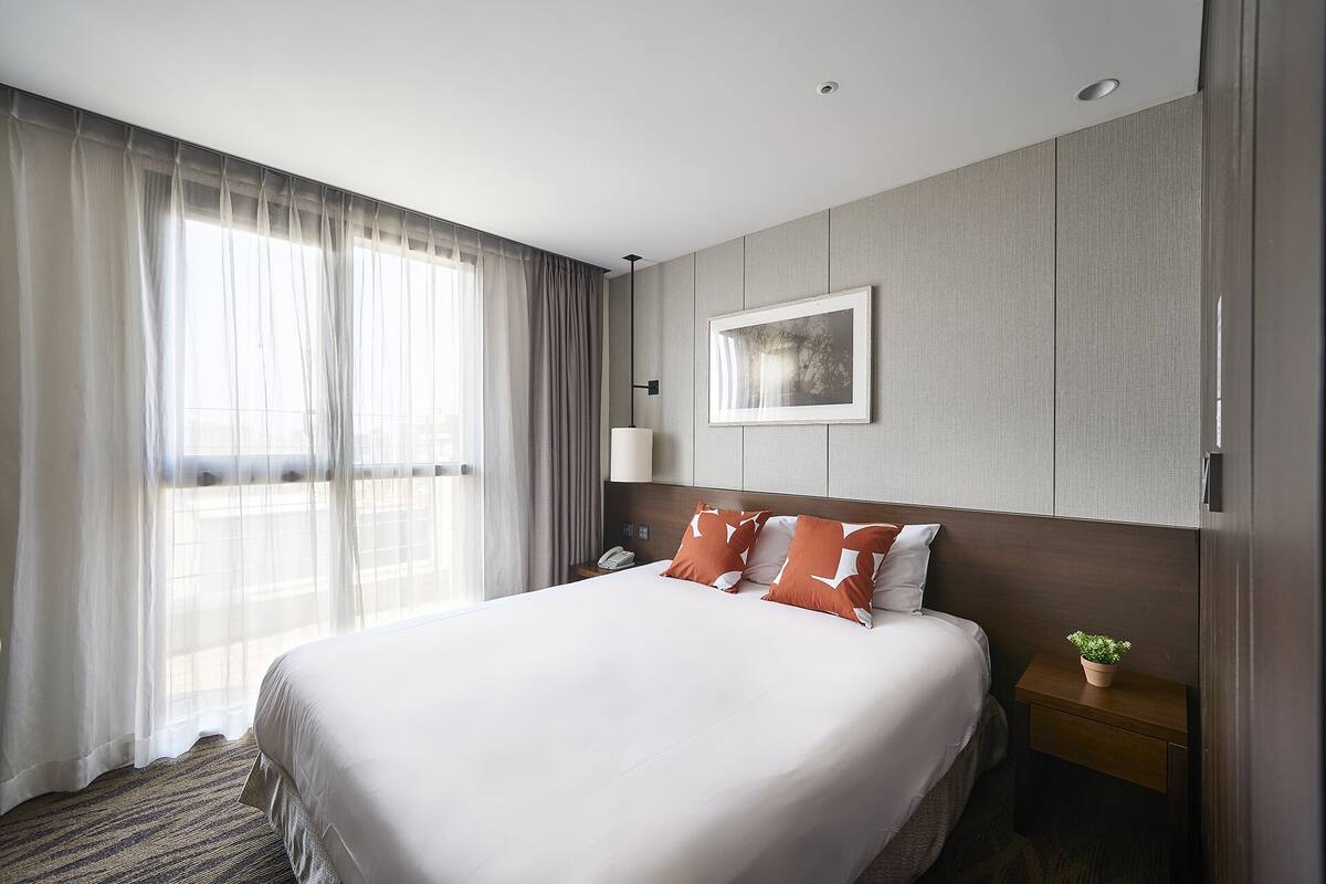 Une chambre d’hôtel avec un grand lit, une table de chevet avec une lampe et un tableau encadré au mur.