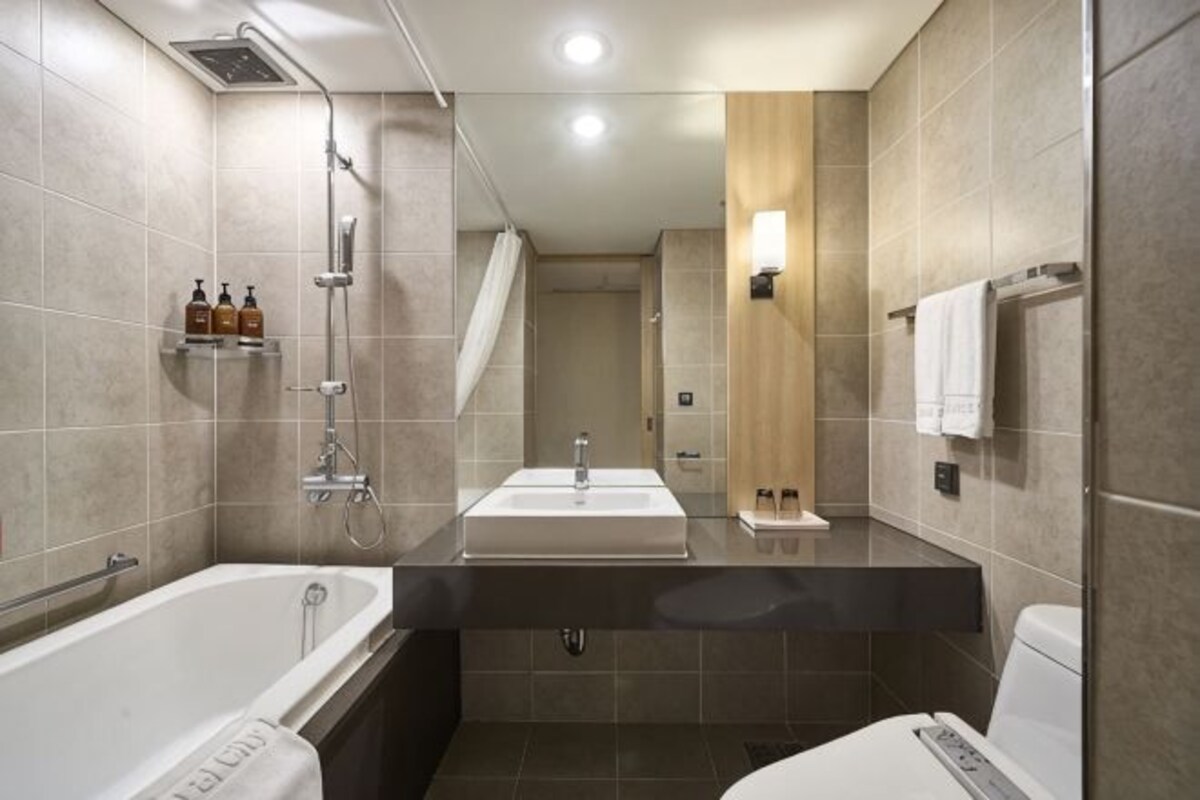 A modern bathroom with a bathtub, two sinks, a shower, and a mirror.