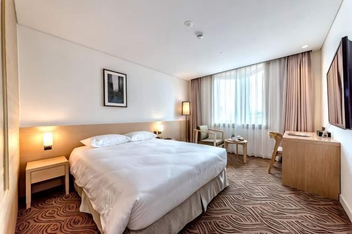 Une chambre d’hôtel avec un grand lit, des tables de chevet, un bureau et une chaise.