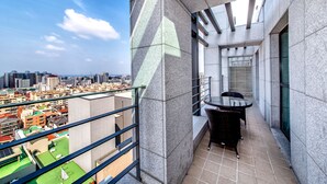 Un balcon moderne avec vue sur la ville, une table en verre et une chaise.