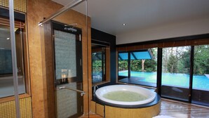 Um banheiro moderno com uma banheira grande, box de vidro e vista para uma piscina.