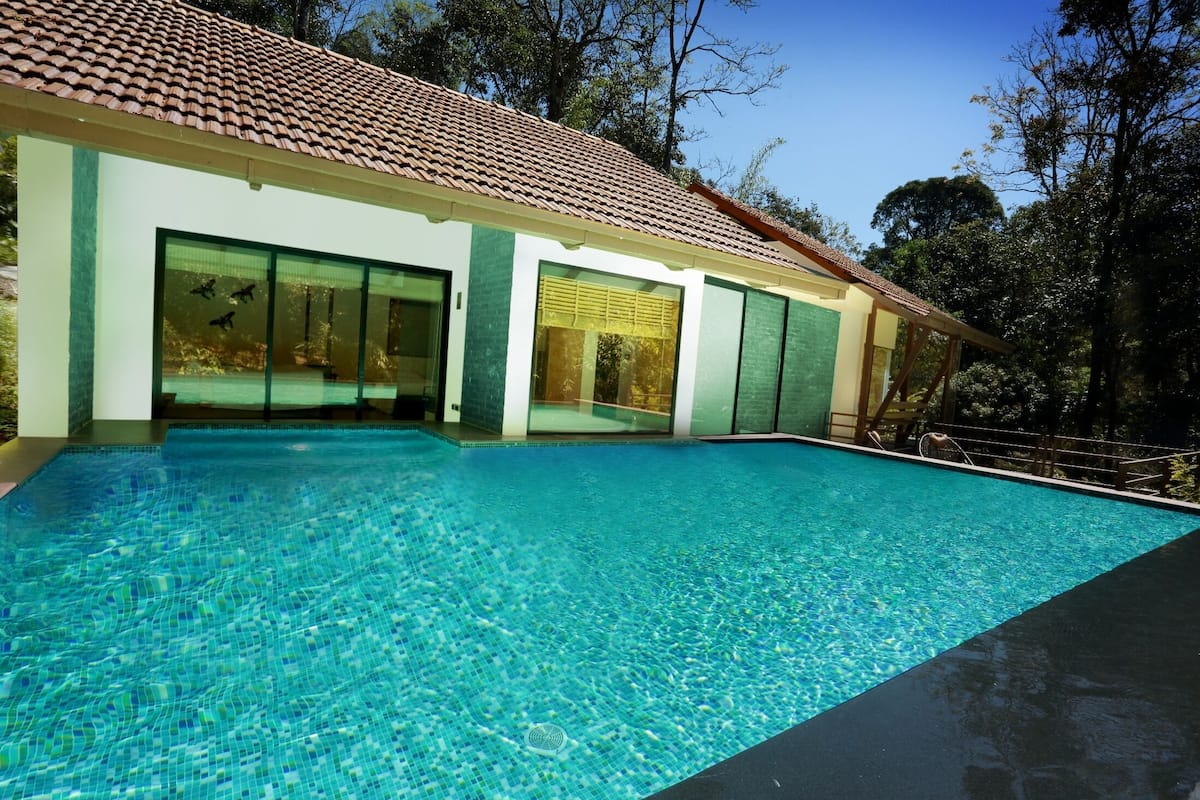 A modern house with a swimming pool, large windows, and a tiled roof.