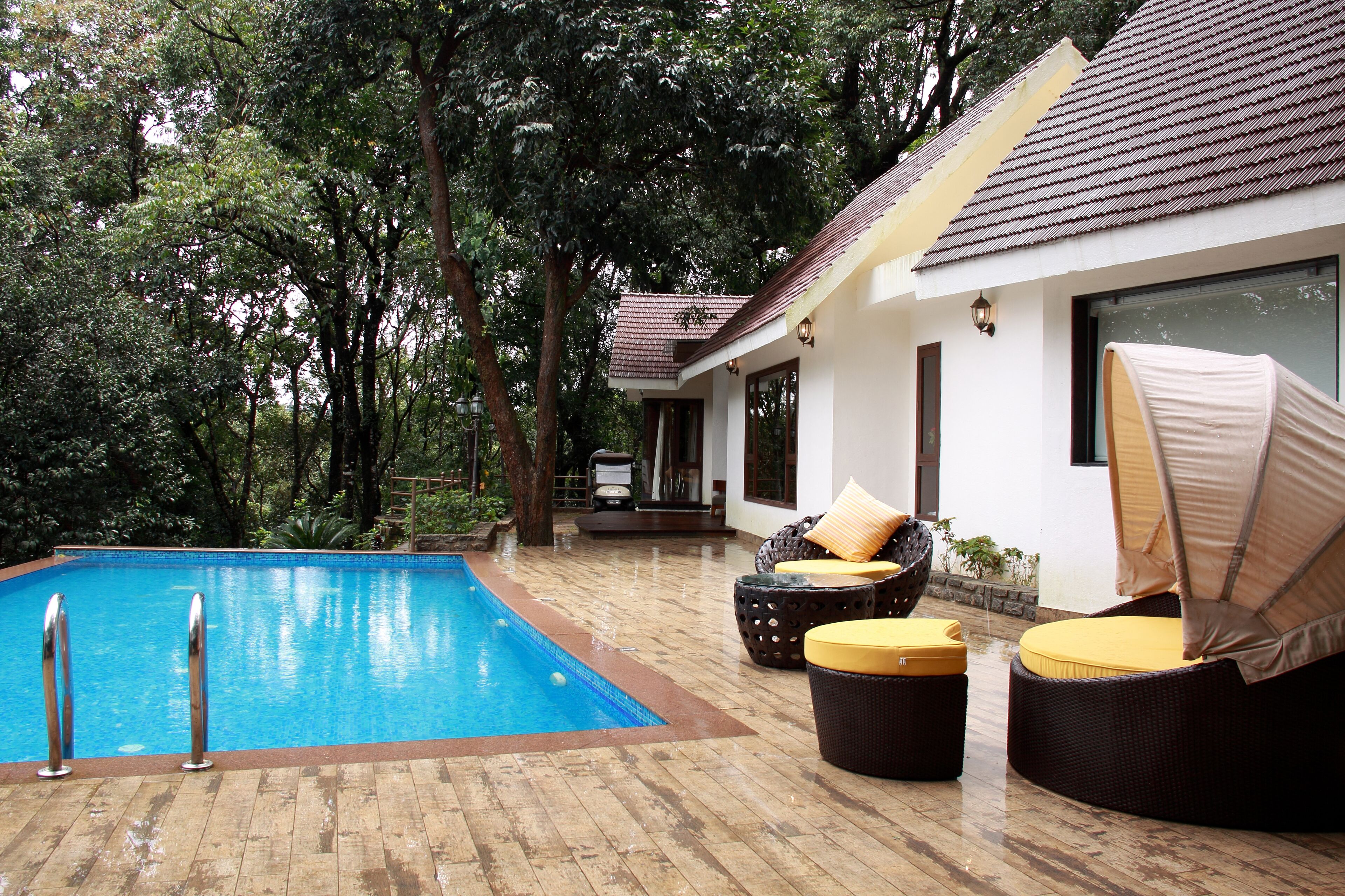 A pool area with a wooden deck, lounge chairs, and a small table.