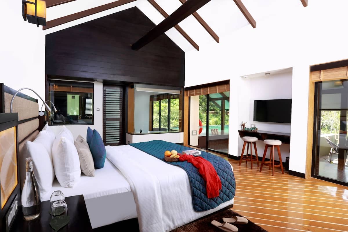 A modern bedroom with a large bed, a desk, and a TV.