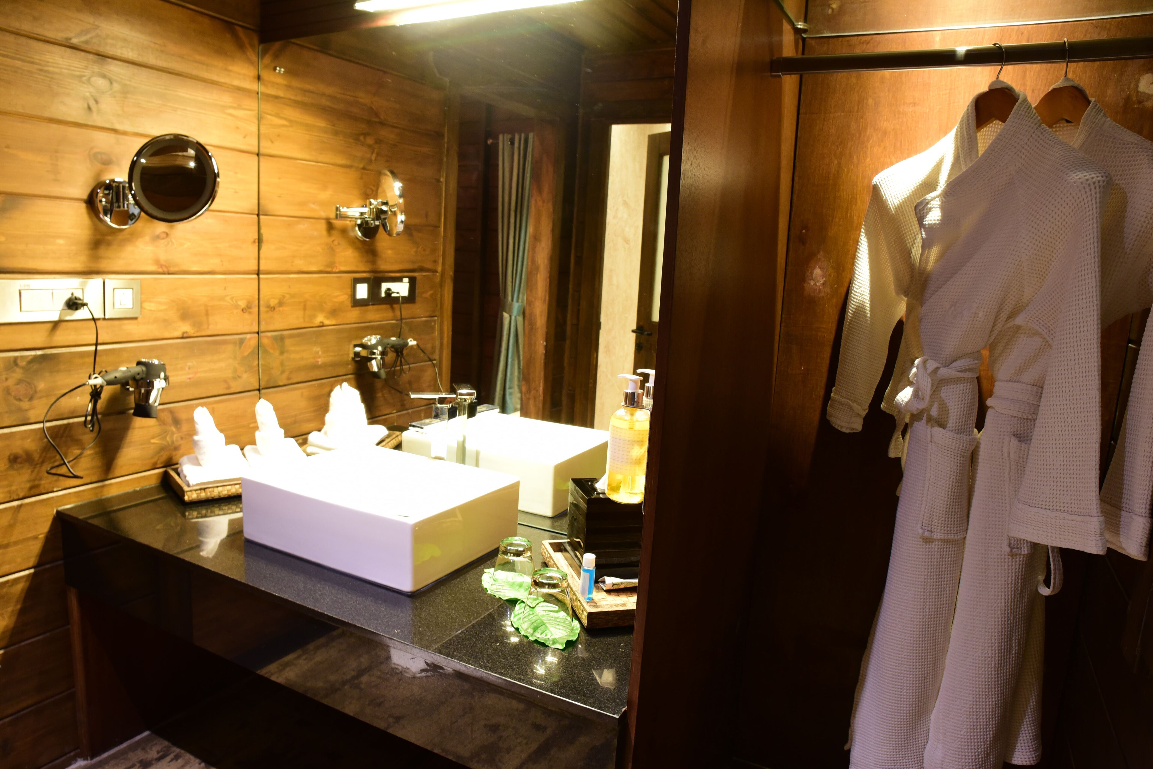 Un baño con paneles de madera, un lavabo doble y un espejo.