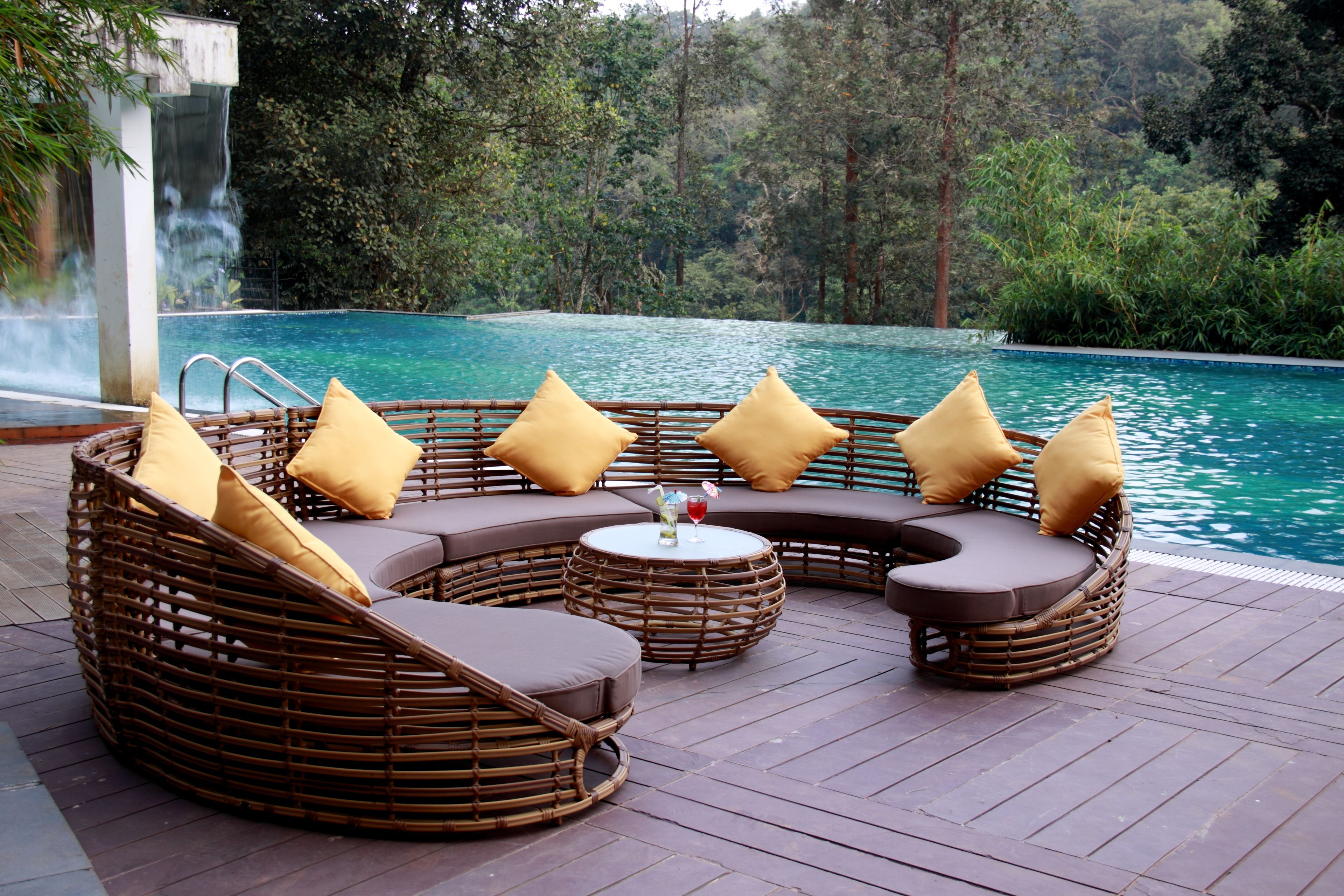A poolside area with wicker furniture and a view of a waterfall.