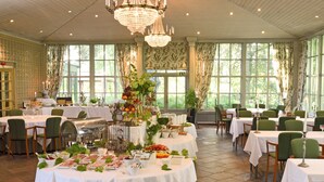 A dining area with round tables, green chairs, and a variety of food and drink options. - Thorskogs Slott (Västerlanda)