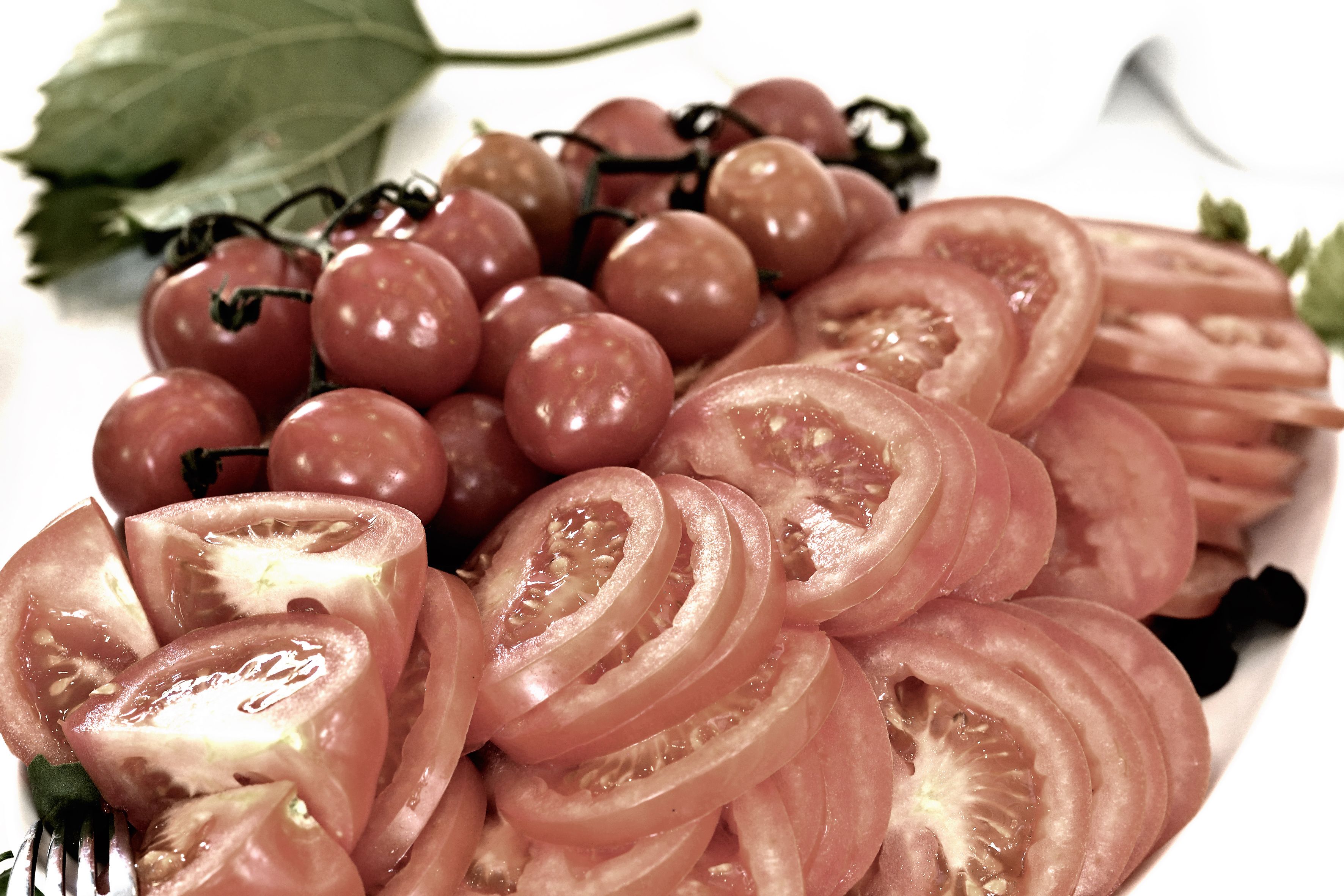 A plate with sliced tomatoes and grapes.